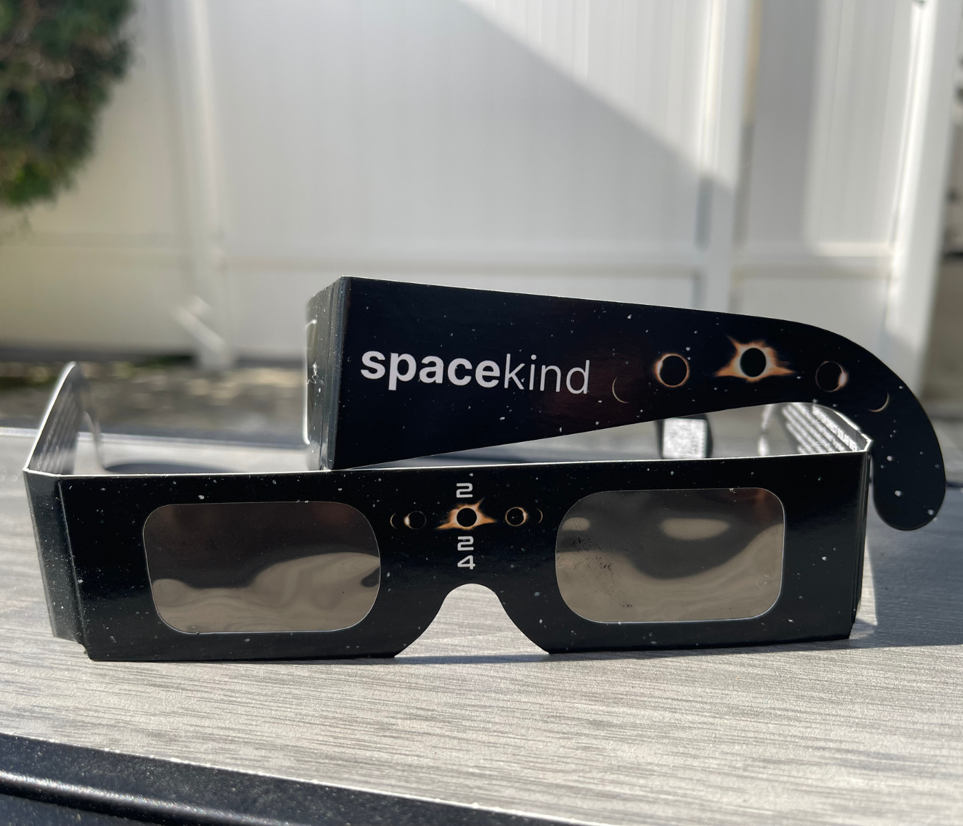 a pair of black eclipse viewing glasses with spacekind branding as well as 2024 on a table