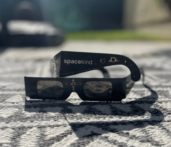 a pair of black eclipse viewing glasses with spacekind branding as well as 2024 on a table